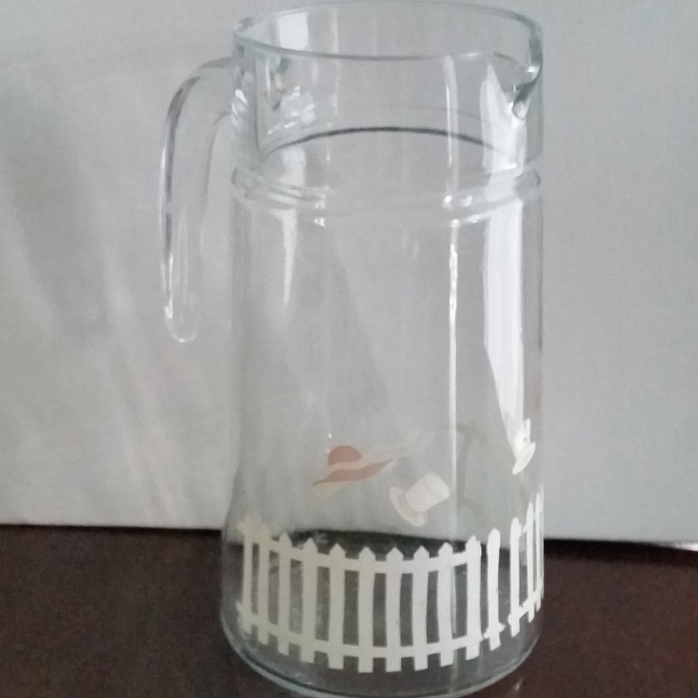 Vintage glass pitcher with white picket fence and hats in the breeze EUC